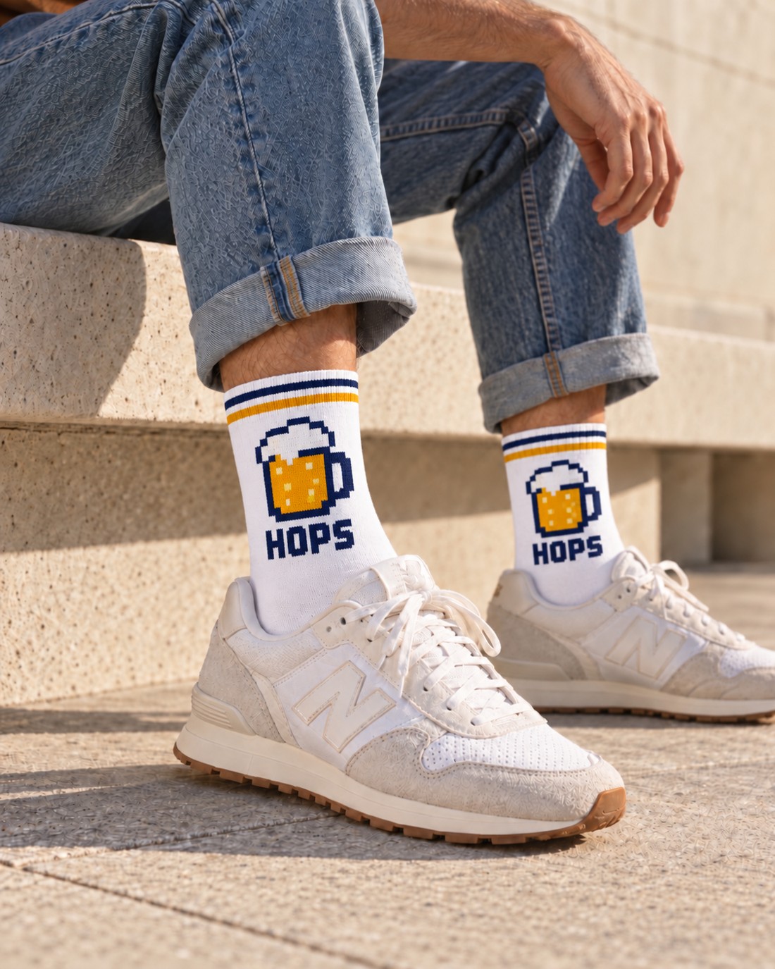Person wearing smooth-knit white beer-themed crew socks with a block-style mug emblem and short ribbed cuffs